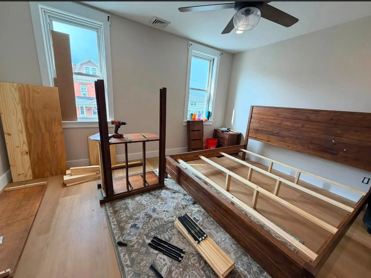 Wooden bed frame being assembled with parts arranged nearby